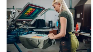 Behind the scenes at Liragap workshop, staff member screen printing a colorful design on a shirt